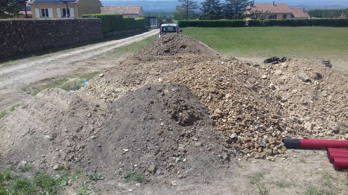 Plusieurs tas de terres et de granulats excavés au bord d’une voie.